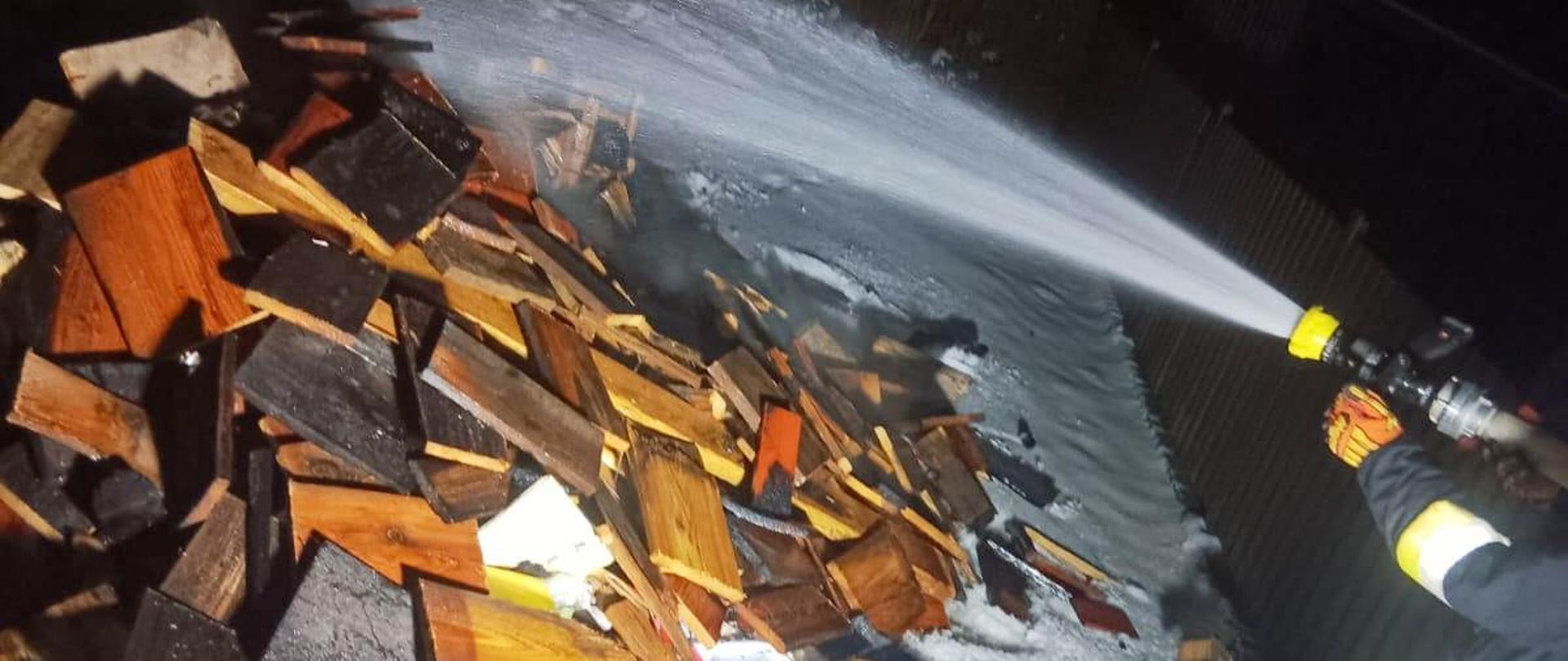 Strażak leje wodę na spalone elementy