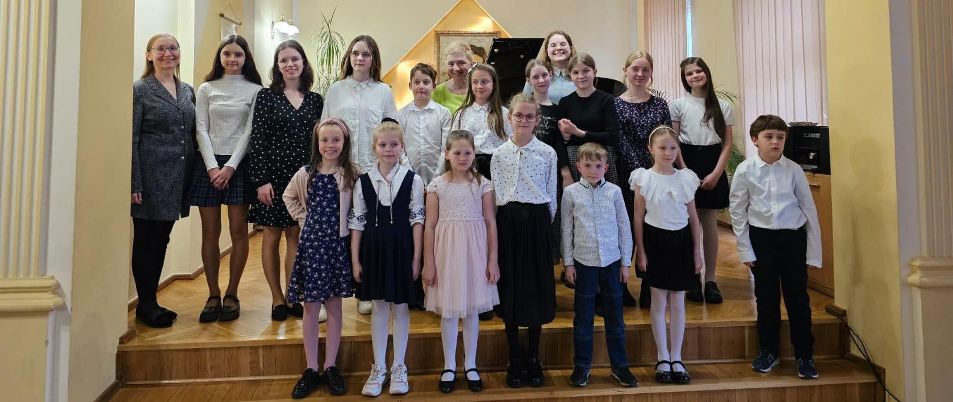 Galeria 17 zdjęć z koncertu uczniów klas fortepianu pt. "Koncert Mój Ulubiony Utwór", który odbył się 17 kwietnia 2024 r. w auli PSM w Kłodzku, uczniowie grają na fortepianie na scenie auli.