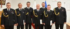 siedmiu strażaków w mundurach wyjściowych pozuje do zdjęcia w sali