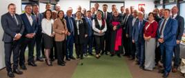 Grupa 29 osób pozuje do zdjęcia w sali konferencyjnej Centrali KRUS.