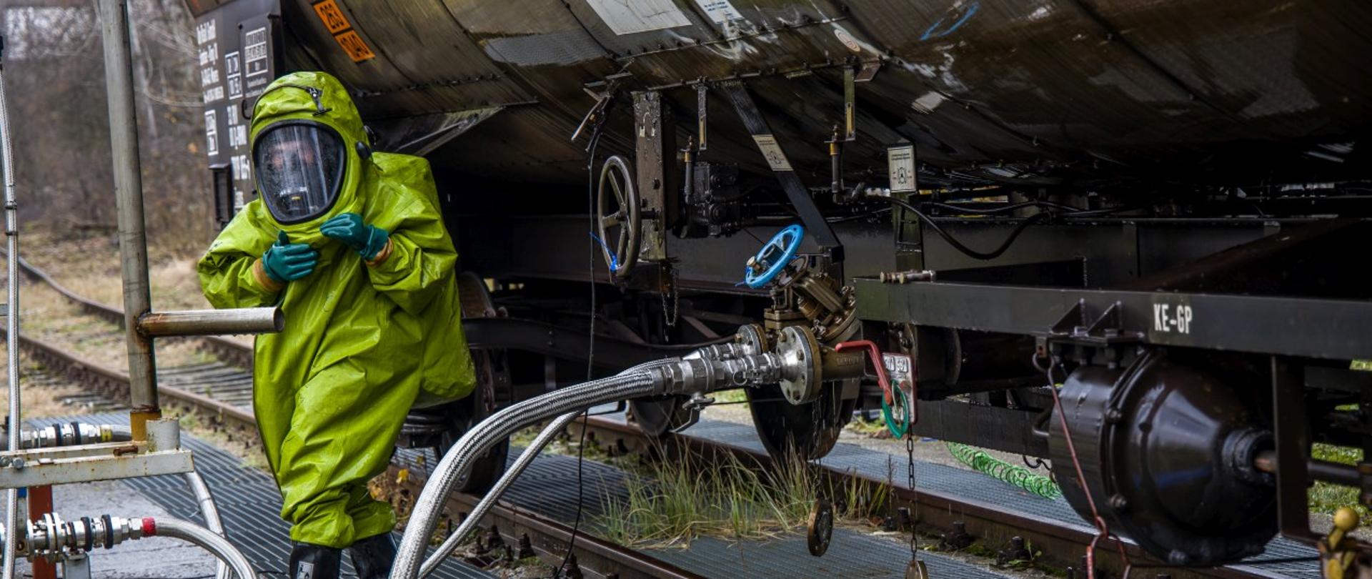 Strażak w ubraniu przeciwchemicznym neutralizuje i uszczelnia wyciek przy cysternie. Działania prowadzone w ramach ćwiczeń na jednym z zakładów przemysłowych w Kędzierzynie-Koźlu.
