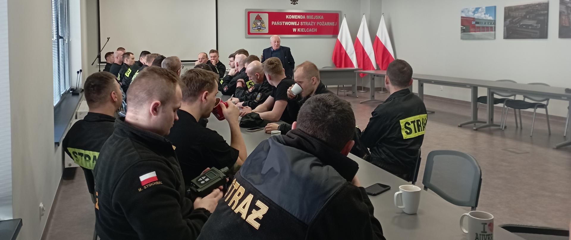 Zdjęcie przedstawia uczestników szkolenia specjalistycznego słuchających prelegenta. Jeden z funkcjonariuszy trzyma w ręku omawiane urządzenia.