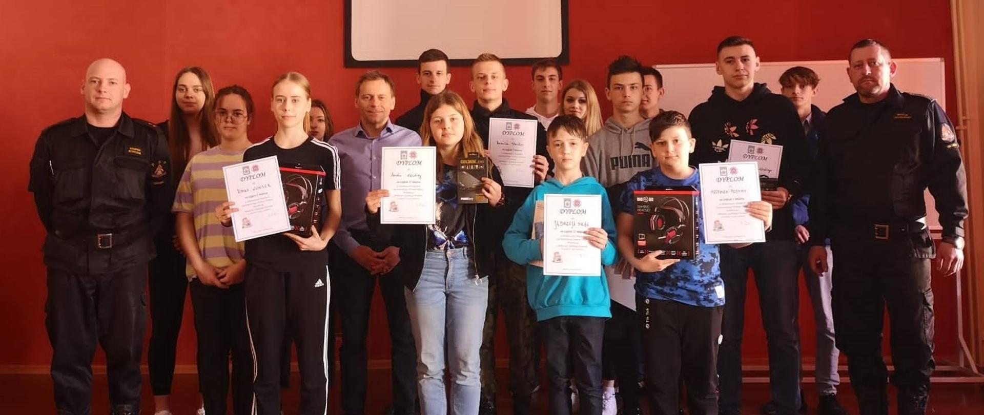 Na zdjęciu znajdują się uczestnicy eliminacji powiatowych OTWP na wspólnym zdjęciu po rozstrzygnięciu konkursu. Uczestnicy wraz z Burmistrzem stoją na scenie auli. 