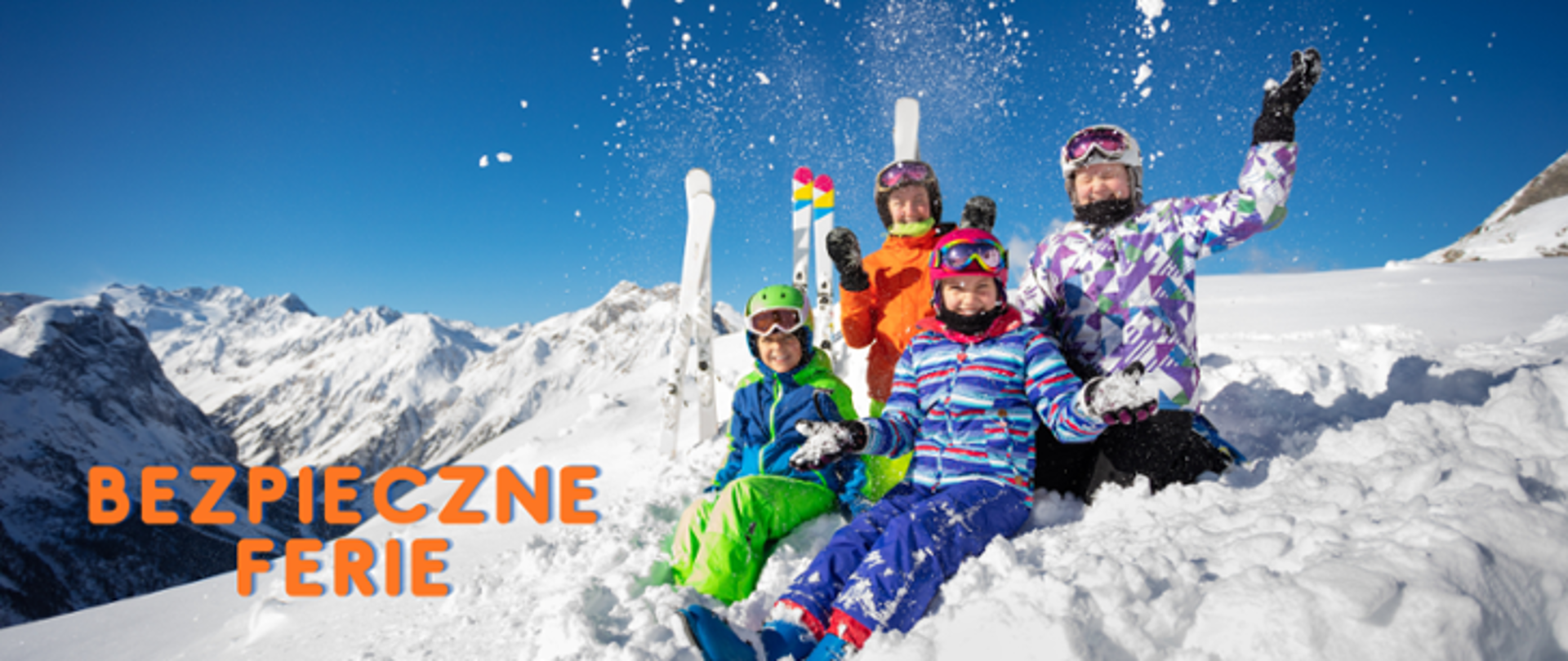 Czwórka dzieci siedzących na śniegu, obok nich narty a w tle góry. Z lewej strony napis Bezpieczne Ferie.