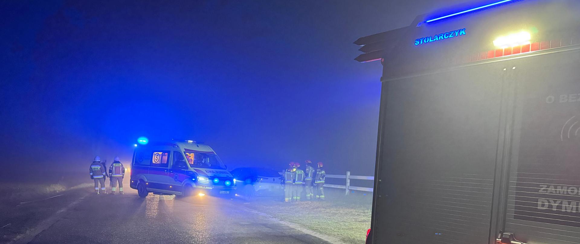 samochód strażacki oraz karetka pogotowia w oddali uszkodzony jeden z samochodów