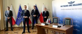 Minister Infrastruktury Dariusz Klimczak wypowiada się podczas briefingu prasowego. W tle wiceminister infrastruktury Piotr Malepszak, a także przedstawiciel PLK SA i wykonawcy