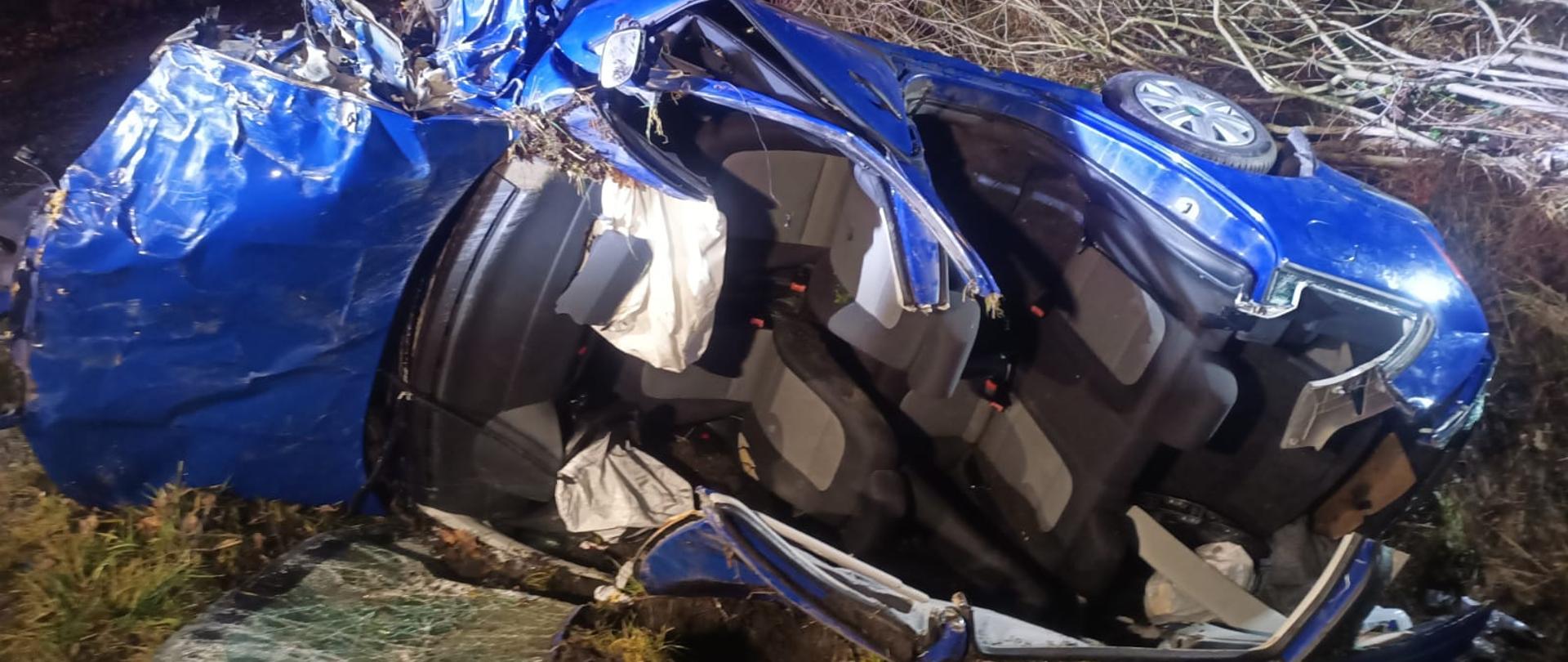 Na zdjęciu znajduje się wrak samochodu osobowego na tle lasu