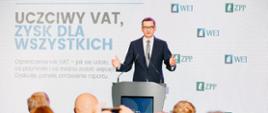 Premier Mateusz Morawiecki stoi przy mównicy na tle napisu: Konferencja uczciwy VAT, zysk dla wszystkich.