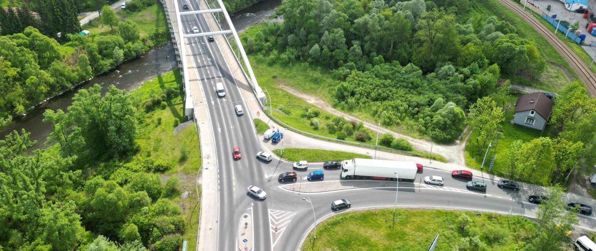 Zdjęcie lotnicze. Widoczny most i skrzyżowanie bez świateł. Spory ruch. Po prawej stronie, widoczny wiadukt kolejowy