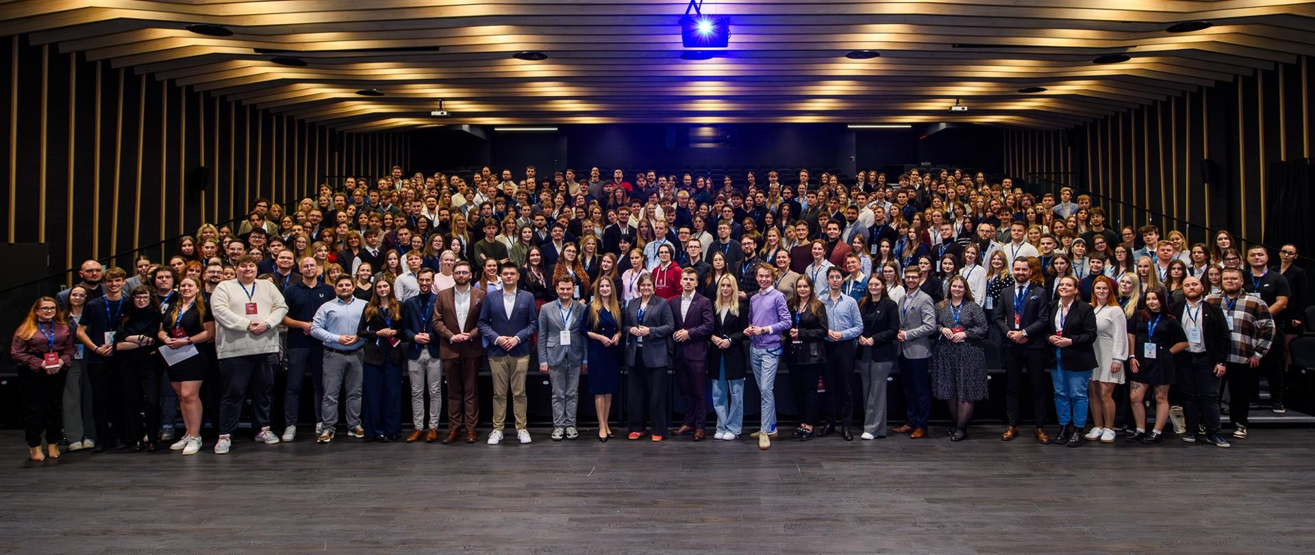 Zdjęcie zbiorowe, w wielkiej sali stoi duża grupa kilkuset osób.