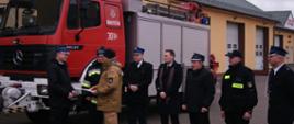 na zdjęciu na tle samochodu strażacy Ochotniczej Straży Pożarnej z Olszyny oraz zastępca Podlaskiego Komendanta Wojewódzkiego PSP podczas uroczystego przekazania samochodu