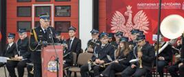 Przemawiający Zastępca Świętokrzyskiego Komendanta Wojewódzkiego na tle orkiestry OSP
