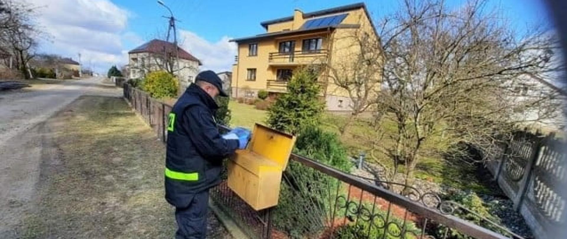 Strażak ochotnicy wrzuca ulotki do skrzynki pocztowej.