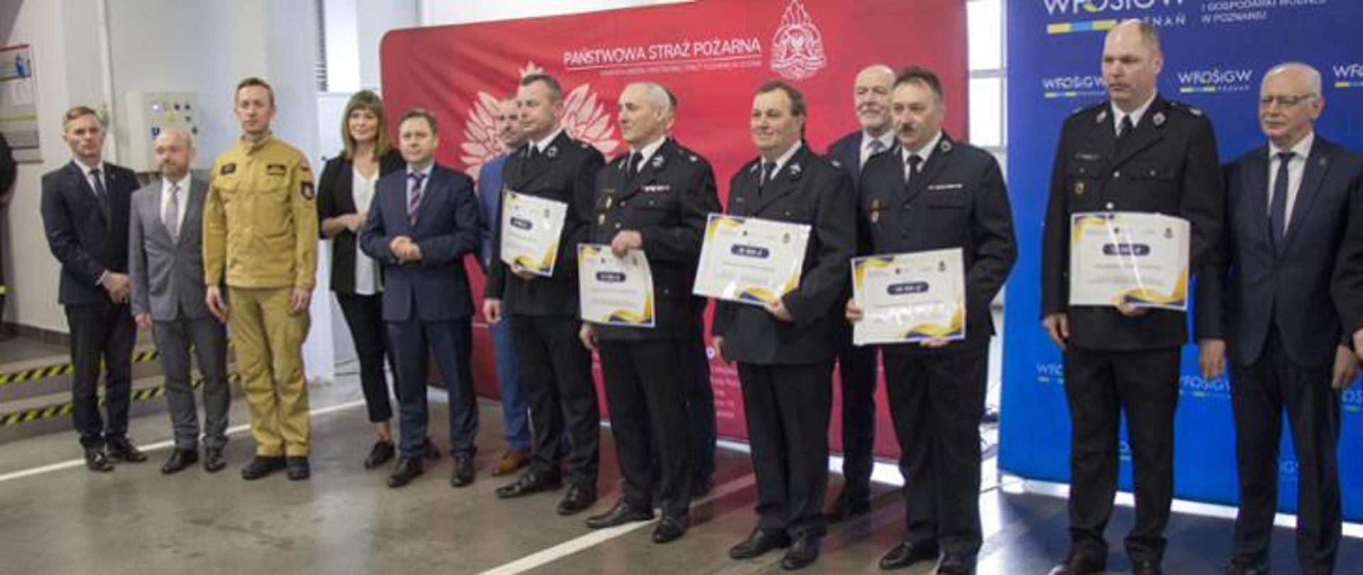 Druhowie oraz zaproszeni goście stoją z otrzymanymi promesami.