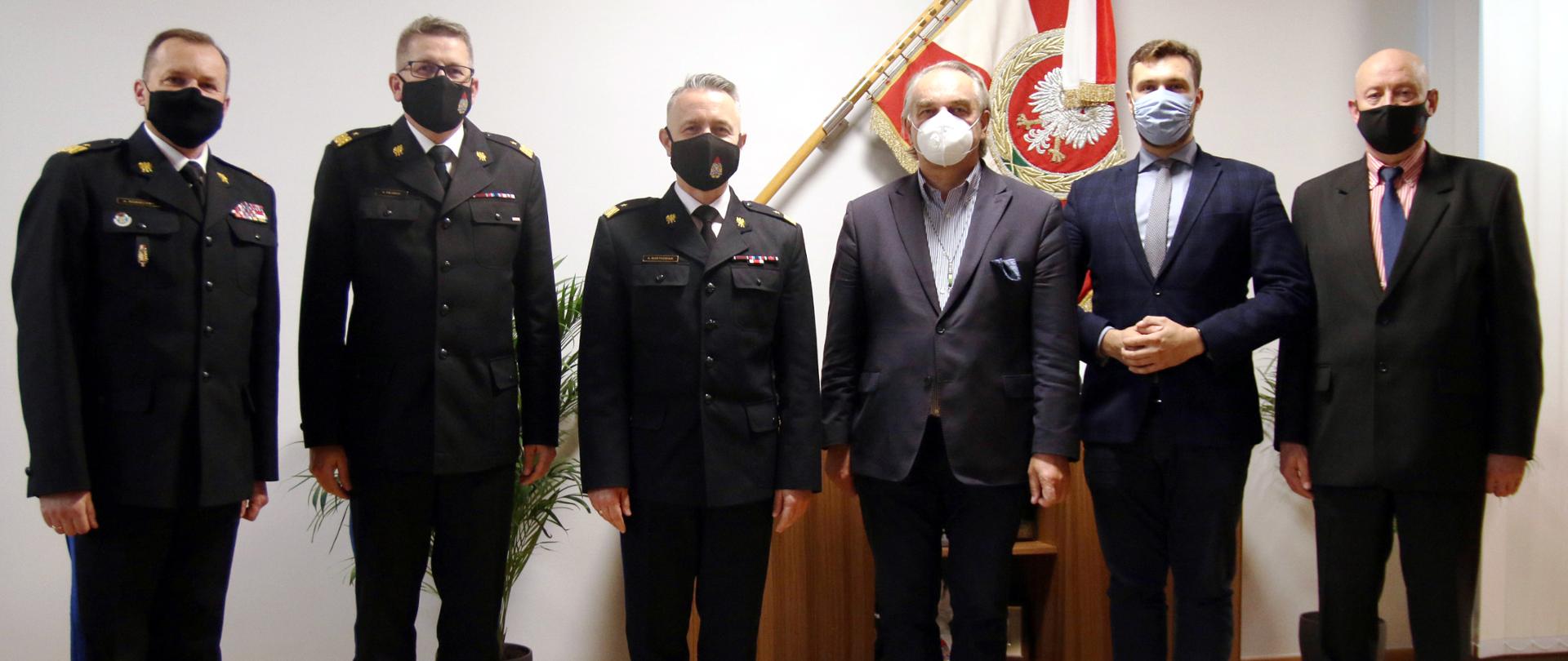 Na zdjęciu komendant główny PSP i jego dwaj zastępcy oraz trzech przedstawicieli Zarządu Głównego OSP RP. Zdjęcie wykonane na tle Sztandaru. Wszyscy uczestnicy są w maseczkach.