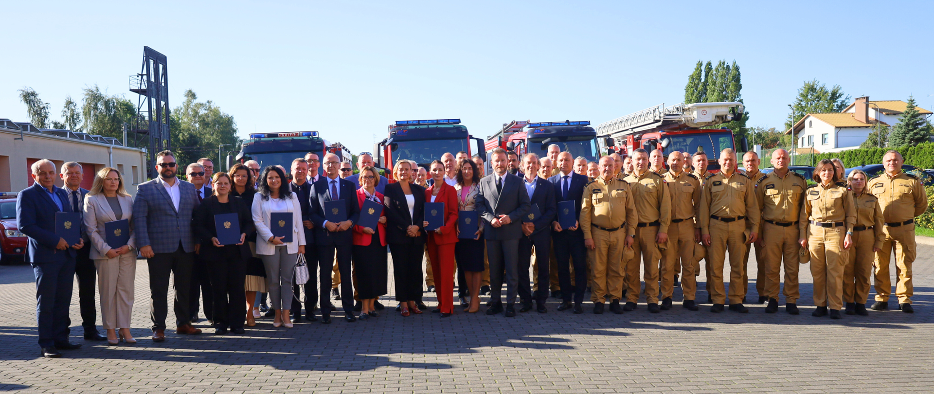 grupa osób stoi na placu, część trzyma w rękach teczki z podpisanymi wcześniej umowami