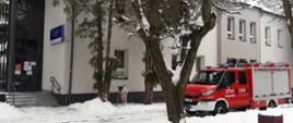 Zdjęcie przedstawia samochód strażacki na tle budynku Niepublicznego Zakładu Opieki Zdrowotnej w Dwikozach. 