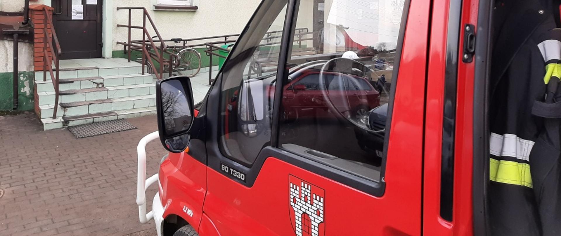 Zdjęcie przedstawia samochód OSP Widawa zaparkowany przed punktem szczepień na terenie gminy Widawa, oraz osobę dowiezioną na szczepienie przez OSP.