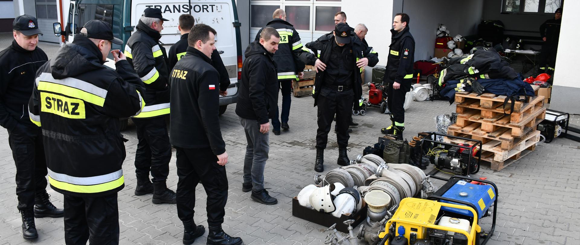 Na zdjęciu widzimy strażaków spisujących i segregujących sprzęt strażacki przekazany przez druhów OSP.