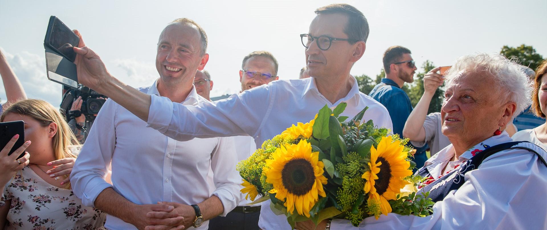 Premier Mateusz Morawiecki robi sobie zdjęcia z mieszkańcami.