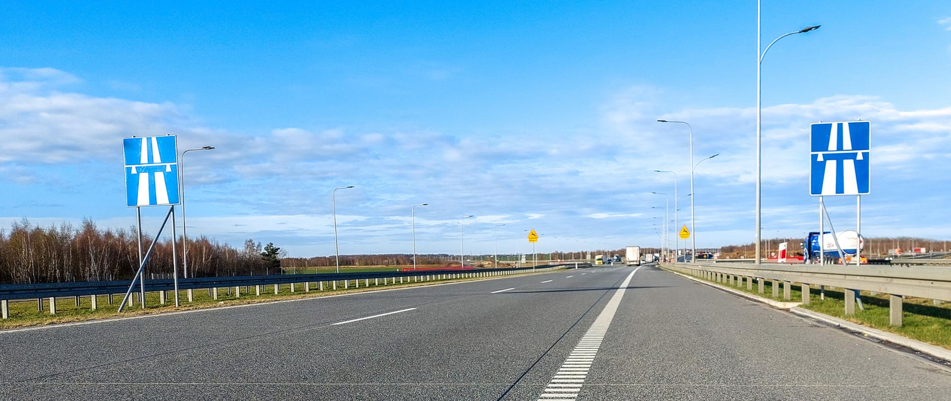 Fotografia z poziomu terenu jezdni autostrady A1. Przy autostradzie ustawiono znaki informujące o początku autostrady.