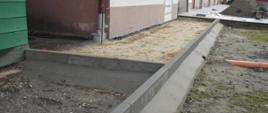Prace remontowe. Plac KP PSP w Rawiczu. Teren przed budynkiem garażowo-warsztatowym. Ułożone są nowe obrzeża oraz przygotowana jest powierzchnia do ułożenia nowej kostki brukowej.