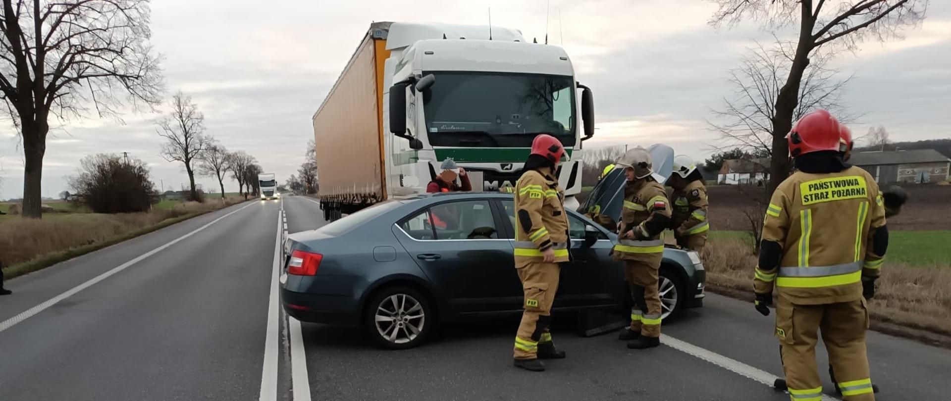 Zdjęcie przedstawia samochód cięzarowy, osobowy oraz strazaków.
