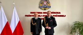 Dwóch funkcjonariuszy na tle ściany z napisem "Komenda Wojewódzka PSP w Szczecinie", po lewej stronie flagi Polski, po prawej kwiat.
Nadbryg. Jarosław Tomczyk wręcza powołanie mł. bryg. Robertowi Dębczakowi