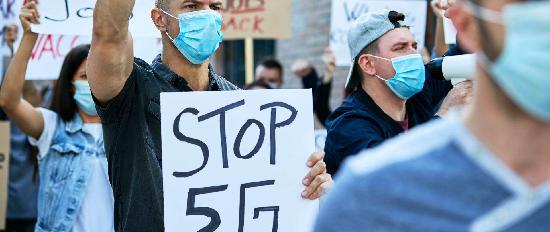 Tłum protestujących, trzymających transparenty "Stop 5G"