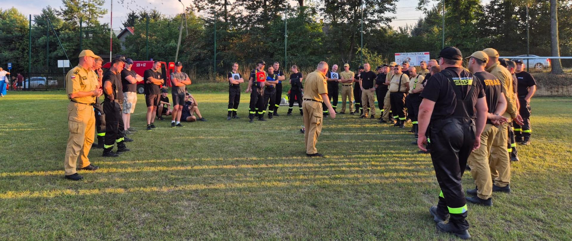 Szkolenie sędziów - grupa strażaków stoi w grupie i słucha prelegenta