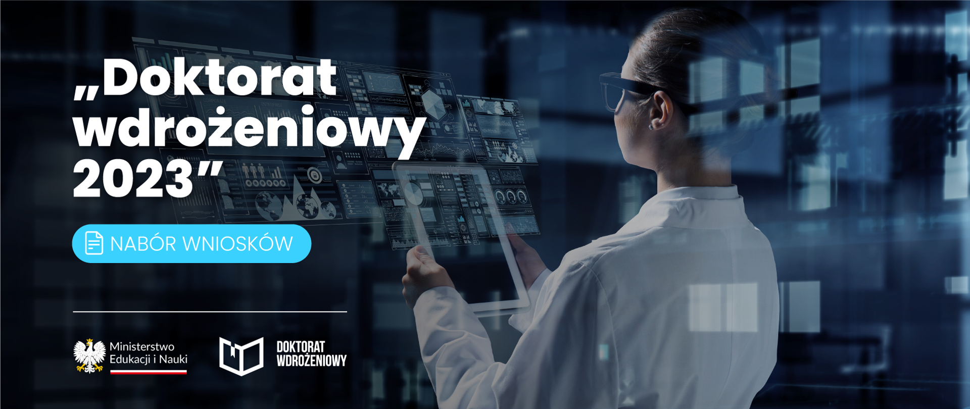 Naukoweic stojący z tabletem w ęku przed nim ekarny przedstawiające różne wykresy. Po lewej stronie napis „Doktorat wdrożeniowy 2023” - nabór wniosków i logotypy Ministerstwa Edukacji i Nauki oraz programu doktorat wdrożeniowy 