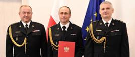 Pomorski Komendant Wojewódzki Państwowej Straży Pożarnej st. bryg. Jacek Niewęgłowski, Zastępca Komendanta Powiatowego Państwowej Straży Pożarnej w Człuchowie bryg. Marcin Owczarski i Komendant Powiatowy Państwowej Straży Pożarnej w Człuchowie st. bryg. Radosław Batruch stoją na tle flagi państwowej i flagi unii europejskiej.