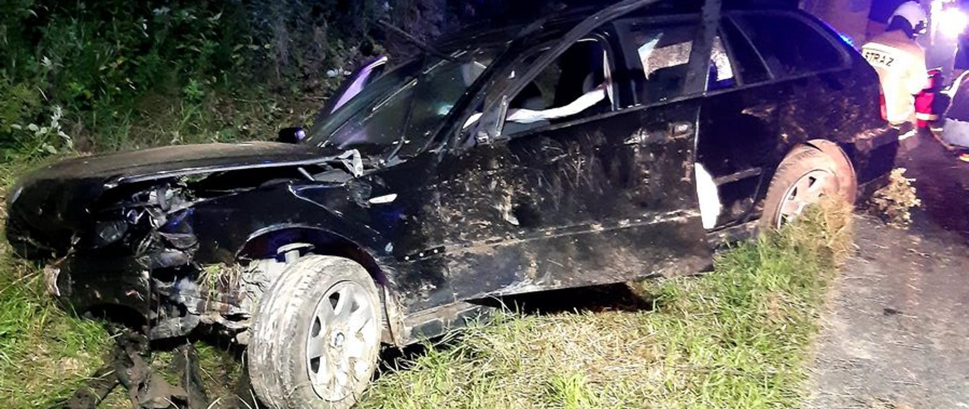 Samochód koloru ciemnego skośnie znajduje się w rowie.