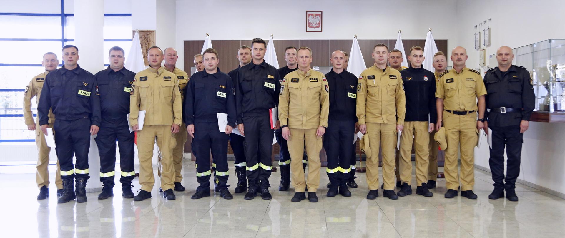 Grupowe zdjęcie uczestników szkolenia (16 funkcjonariuszy PSP) w towarzystwie Zastępcy Komendanta Centralnej Szkoły PSP oraz dwóch funkcjonariuszy CS PSP