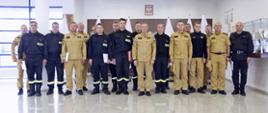 Grupowe zdjęcie uczestników szkolenia (16 funkcjonariuszy PSP) w towarzystwie Zastępcy Komendanta Centralnej Szkoły PSP oraz dwóch funkcjonariuszy CS PSP