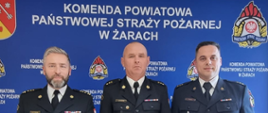 Strażak otrzymujący nagrodę z Komendantem i Zastępcą Komendanta