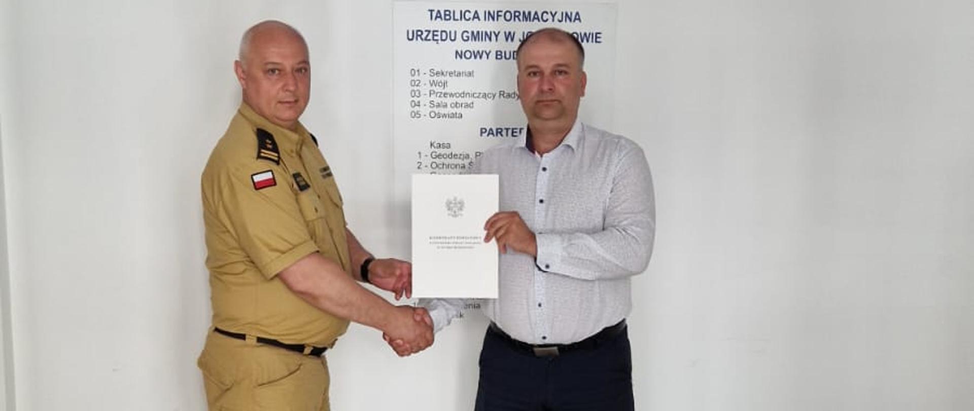 Zdjęcie przedstawia komendanta powiatowego PSP w Suchej Beskidzkiej bryg. Krzysztof Okrzesika oraz wójta gminy Jordanów Artura Kudzię trzymającego przed sobą podpisane porozumienie. 