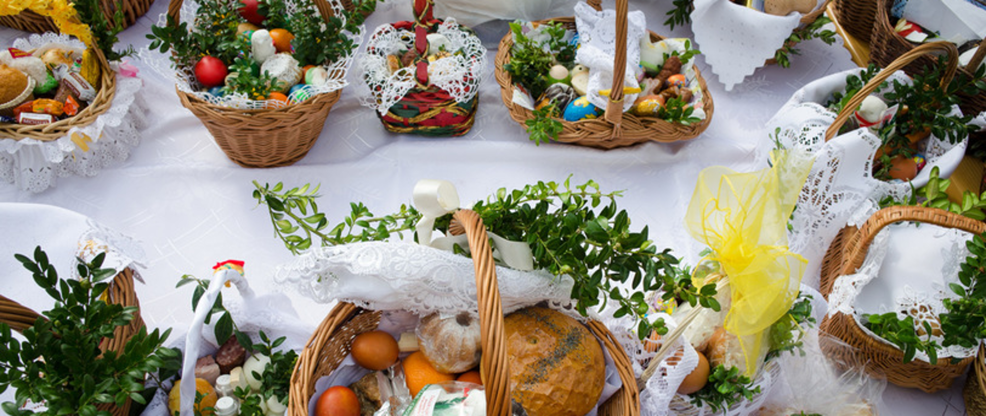 Na zdjęciu widoczny jest stół na którym ułożone są udekorowane koszyczki świąteczne z produktami do spożycia podczas Świąt.