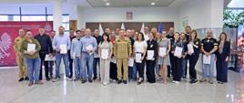 Pamiątkowe zdjęcie grupowe uczestników szkolenia inspektorów ochrony przeciwpożarowej (28 osób) w towarzystwie Zastępcy Komendanta Centralnej Szkoły PSP, kobiety oraz funkcjonariusza CS PSP