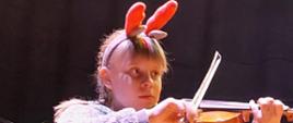 Dziewczynka w przebraniu łosia gra na skrzypcach.