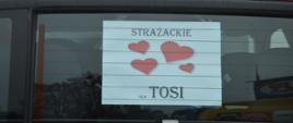Korowód Wielkich Serc. Fragment strażackiego samochodu rozpoznawczo-ratowniczego. Na tylnej szybie naklejony plakat z napisem "STRAŻACKIE SERCA DLA TOSI"