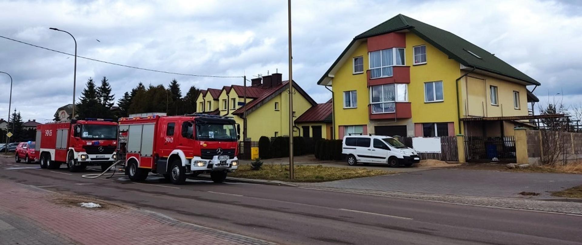 Samochody pożarnicze stoją na ulicy przed budynkiem 