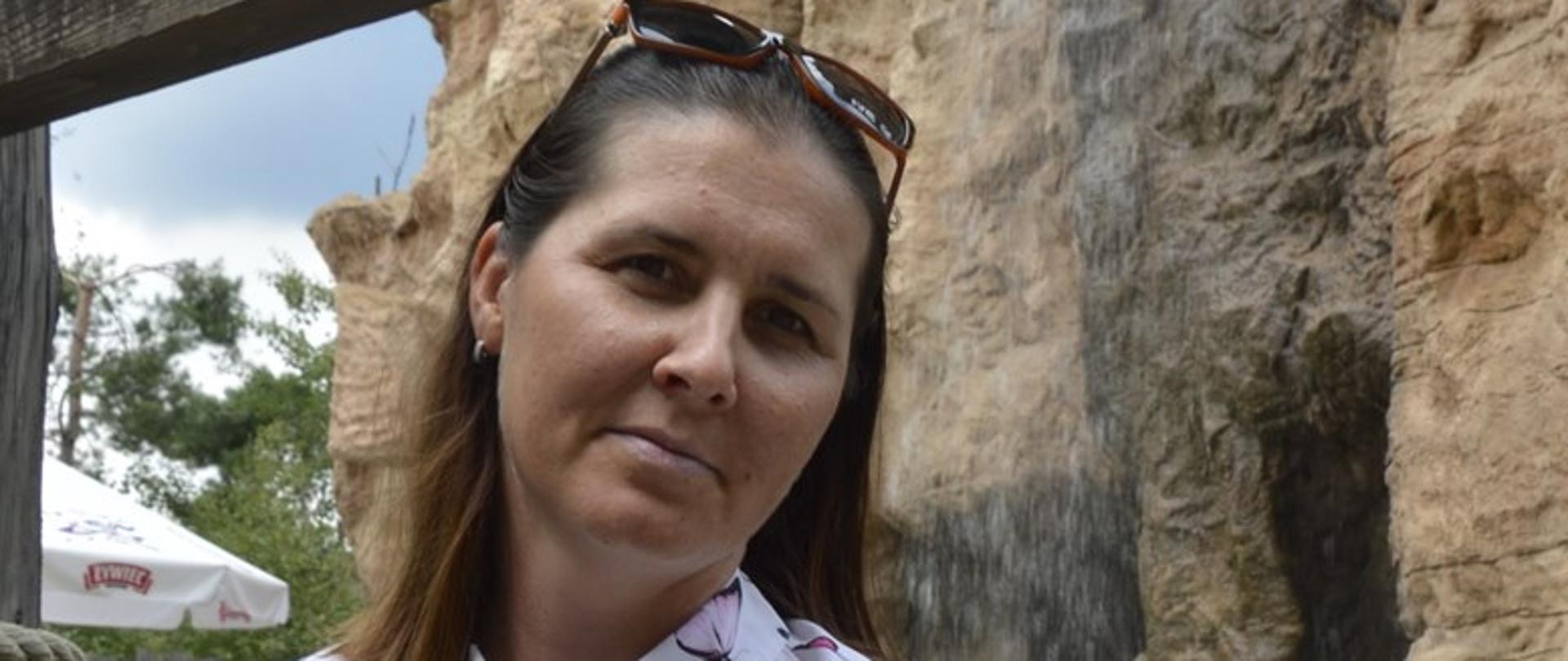 Na zdjęciu jest kobieta na tle skał i wodospadu