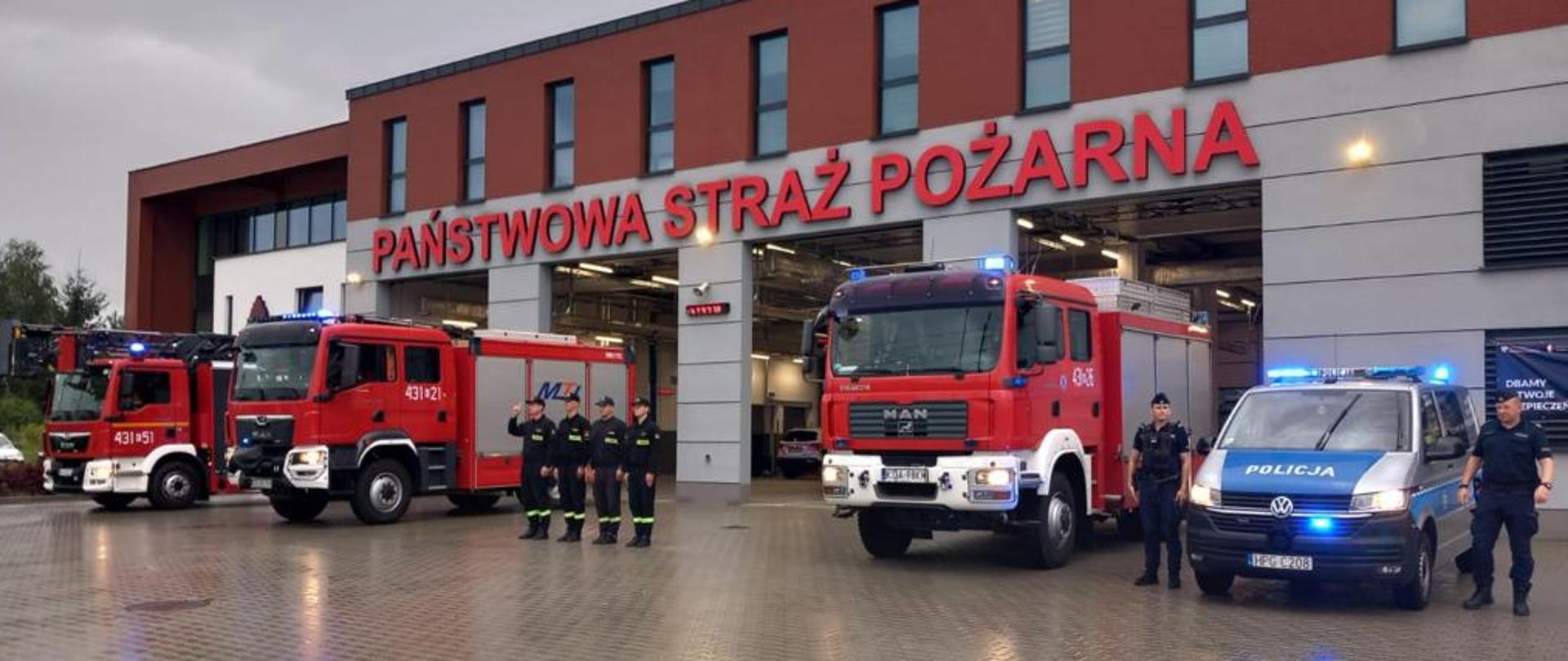 Na zdjęciu strażacy przed budynkiem wraz z policjantami 