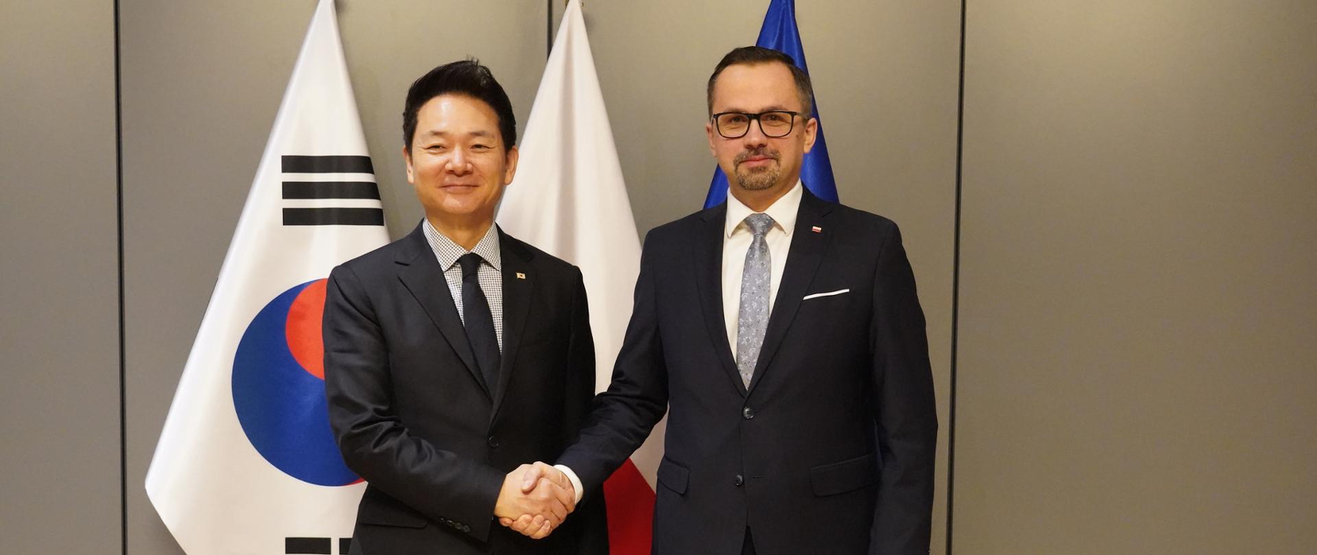 Dwie osoby stoją obok siebie. Drugi z prawej stoi wiceminister Marcin Horała.