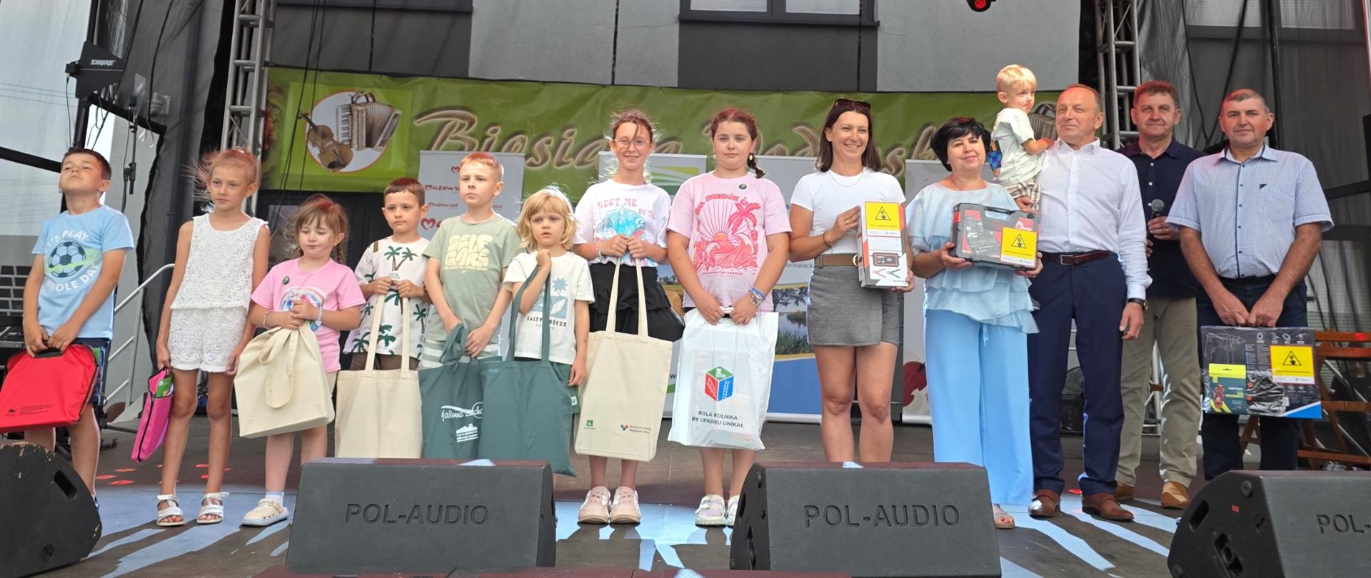 Na scenie stoi pięcioro dorosłych i ośmioro dzieci. Dwie kobiety i mężczyzna oraz wszystkie dzieci trzymają nagrody wręczone przez organizatorów konkursu.
