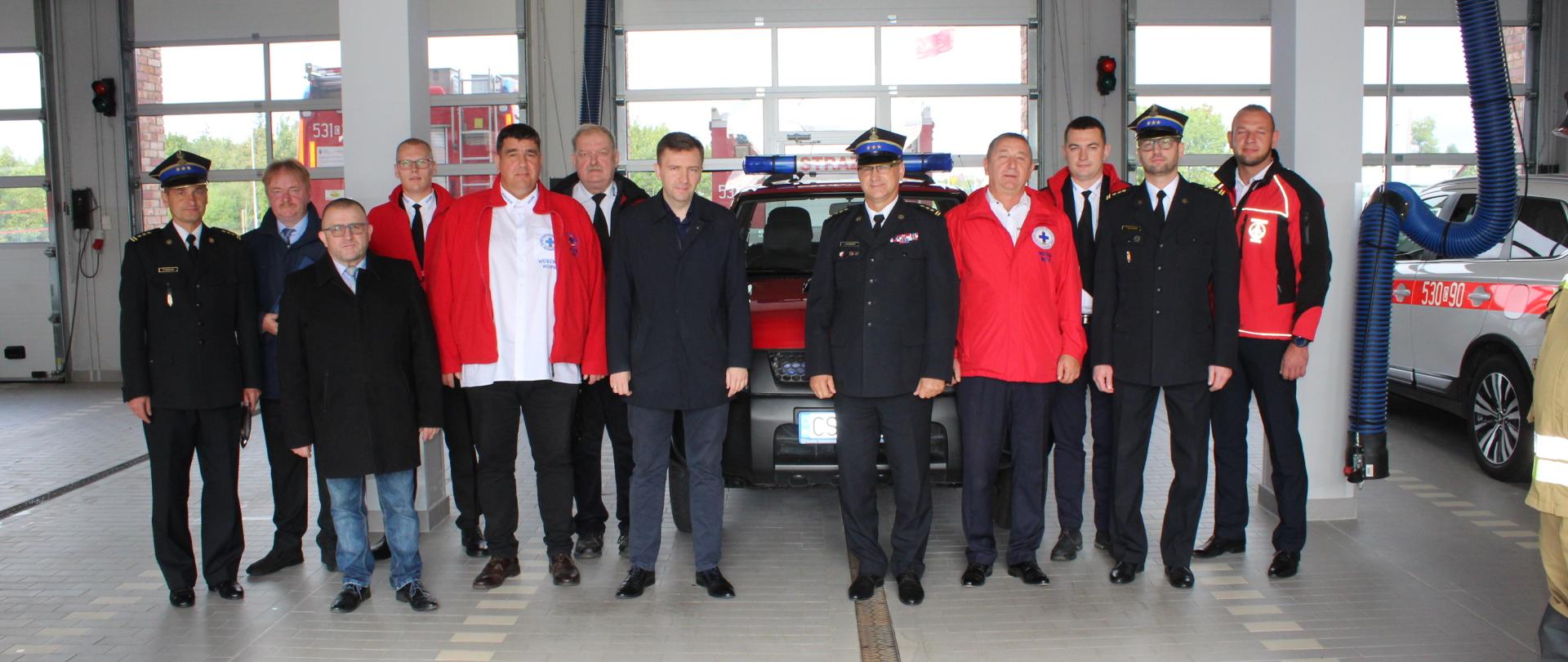 W garażu Komendy Powiatowej Państwowej Straży Pożarnej w Świeciu na tle samochodu Nissan Pickup stoją uczestnicy uroczystości przekazania samochodu dla Wdeckiego Wodnego Ochotniczego Pogotowia Ratunkowego.
