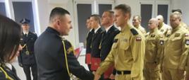 Komendant Powiatowy Państwowej Straży Pożarnej w Lwówku Śląskim wręcza akt mianowania nowo mianowanemu strażakowi podczas uroczystej zbiórki PSP.