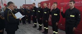 Pięciu strażaków ustawiony w rzędzie, z podniesioną ręką składa ślubowanie. 