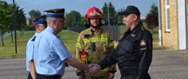 Strażak komendant ściska dłoń strażakowi który uzyskał awans